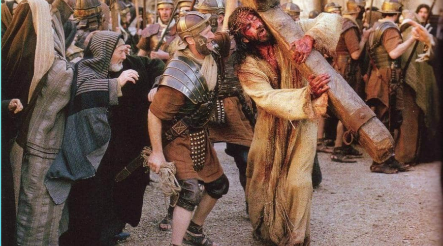 Picture of Jesus carrying the cross as people scoff at him. Text in image says, "Are Christians Hospitable to Christ or are we the Romans and Jews scoffing at him?