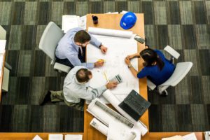 Three people working closely around a table like a family.