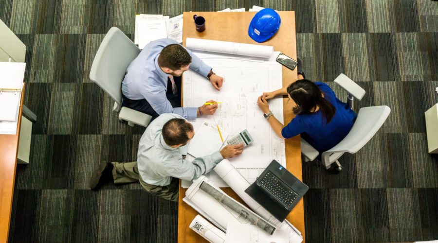 Three people working closely around a table like a family.