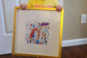 My daughter, Age 2, holding a gift of her artwork in a golden frame.