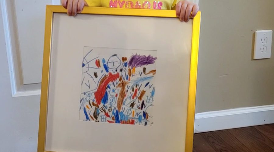 My daughter, Age 2, holding a gift of her artwork in a golden frame.