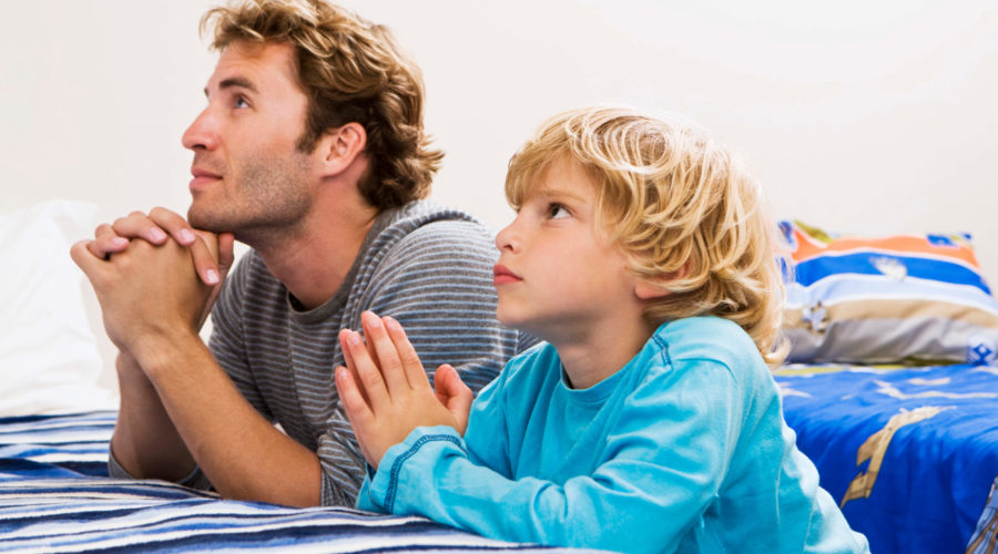 Dad and son praying at a bed